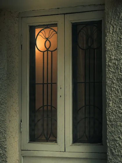 The warm glow from a window on a dark, rainy evening. The art deco grill adds a touch of vintage character to this moody, atmospheric shot.