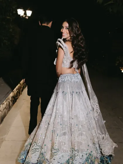 A beautiful shot of the bride from the back, showing the flow of her lehenga and her soft, wavy hair.