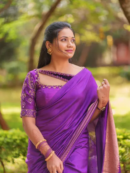 A beautiful outdoor shot highlighting the detailed beadwork and embroidery on the neckline and sleeves of this purple rental blouse.