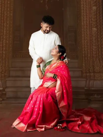 A beautiful moment between the couple, dressed in traditional attire. The rich pink saree and the classic setting create a portrait that is full of cultural pride.