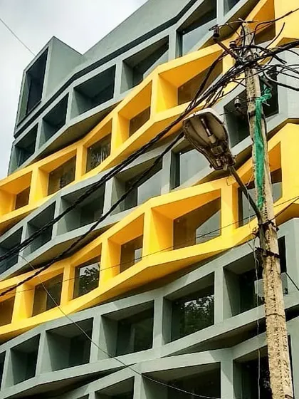 Another angle of the commercial project in Indiranagar during construction. The image highlights the three-dimensional quality of the yellow facade elements as they wrap around the building.