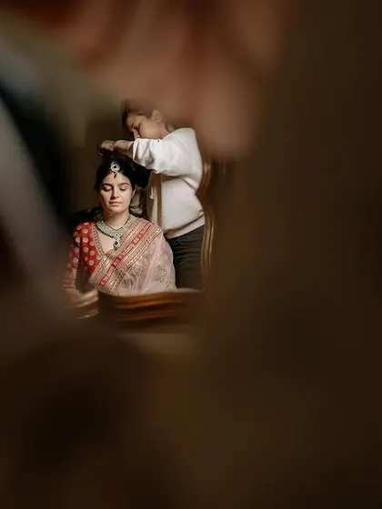 An artistic shot of the bride getting ready, seen through a reflection, capturing the quiet moments of preparation.