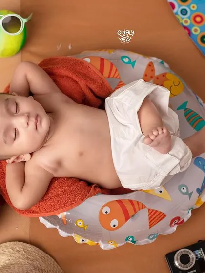 Too hot, but still cool. A baby relaxes on a mini beach chair, enjoying a nap with a coconut drink by his side.