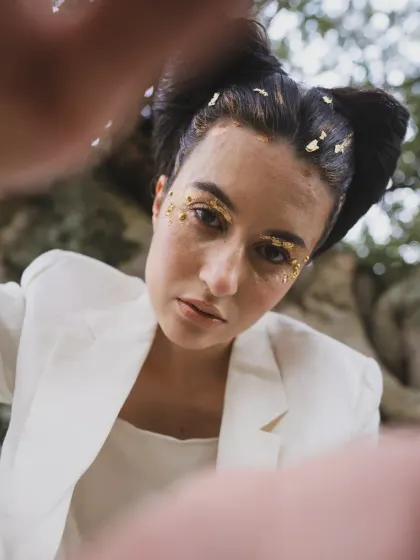 A close-up from the 'SOLARA' shoot, focusing on the gold leaf makeup and the model's direct gaze. This highlights the importance of beauty and styling working together to create a cohesive artistic vision.