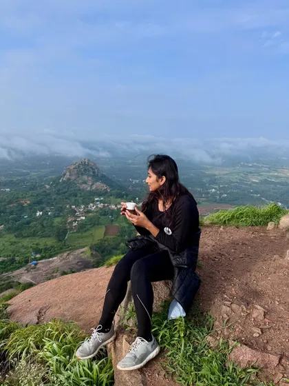 A trekker enjoying a quiet cup of tea at the top of Uttari Betta, soaking in the peaceful morning and the beautiful view.