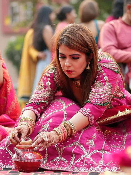 The client is focused on the puja rituals, her hands decorated with traditional mehendi.
