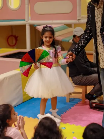 The birthday girl participates in a magic show, holding a colorful fan. We love to make the guest of honor a part of the entertainment.