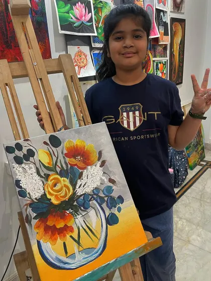 A young student proudly shows off her beautiful floral bouquet painting. She learned how to use different brushstrokes to create a variety of flower shapes and textures.