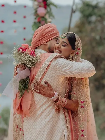 A tender hug between the bride and groom after their jaimala, a moment of quiet connection amidst the celebration at their lakeside wedding.