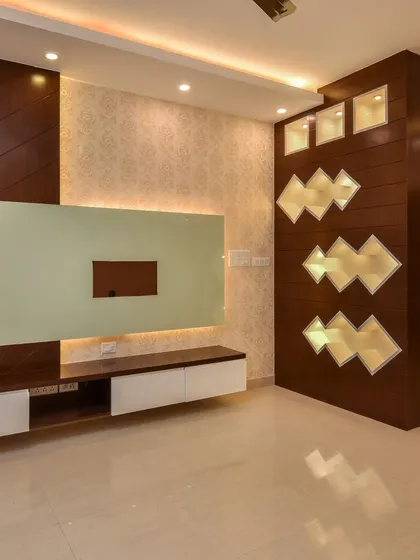 A full view of a living room featuring a floating TV console and a decorative partition with backlit geometric cutouts. The design balances modern aesthetics with warm, inviting lighting.