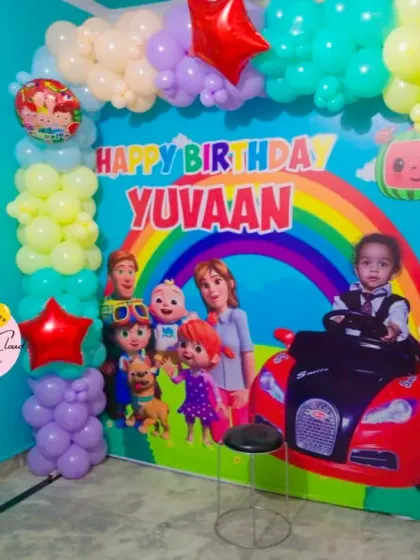 A full-wall Cocomelon birthday backdrop with character prints and a colorful balloon frame.