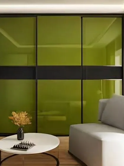 We designed this modern wardrobe with vibrant green lacquered glass panels and a black frame. The sliding doors save space while adding a bold pop of color to the room, creating a functional and stylish storage solution.