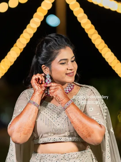 A candid moment of the bride putting on her earrings, which perfectly match the ruby choker.