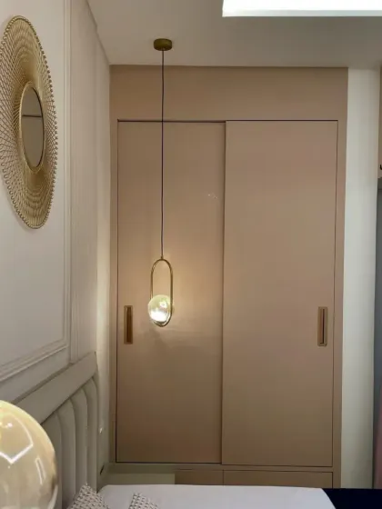 This image showcases the sliding wardrobe and the unique gold-toned circular mirror, adding a touch of glamour to the bedroom's decor.