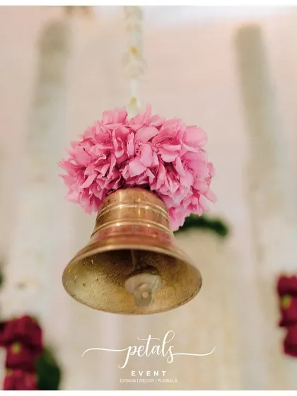 A close-up of a traditional temple bell, adorned with a pink flower. These small details add an authentic and sacred touch to the decor.