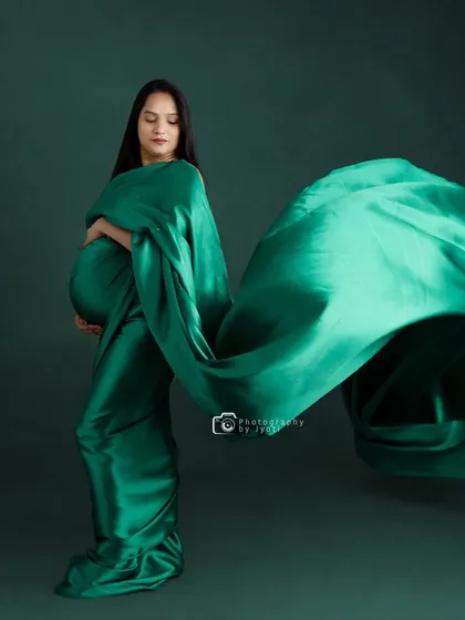 A dramatic studio shot with a flowing emerald green fabric, creating a sense of motion and elegance.