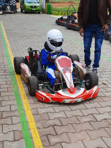 A young driver in his kart in the pit lane.