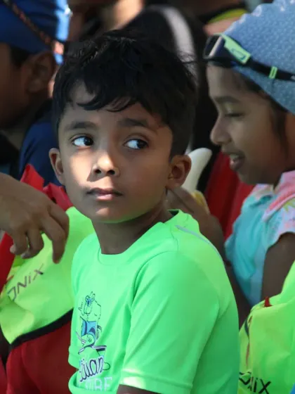 A young boy listens intently during a poolside briefing. Safety and clear instruction are our top priorities before any swimming activity begins.