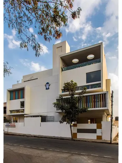 The 'Toy Story' preschool building, designed to be a playful and imaginative space for young children. The facade features colorful vertical louvers and a large, cantilevered volume with circular cutouts, creating a building that looks like it's ready for fun.