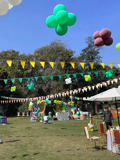 A wide view of the outdoor jungle party, showing the main stage in the distance and themed decorations hanging overhead.