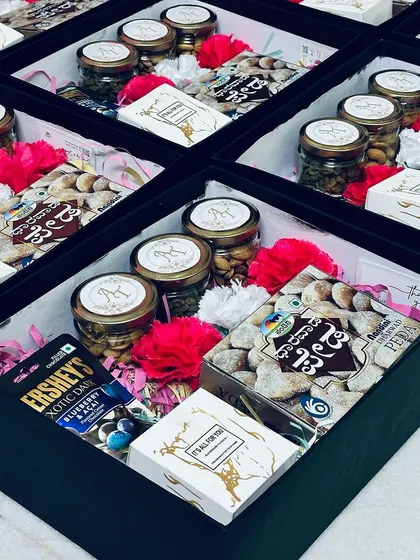 A look inside our wedding favor boxes. This one features a mix of traditional and modern treats, including a box of Nandini Dharwad Peda, jars of dry fruits, and Hershey's chocolates.