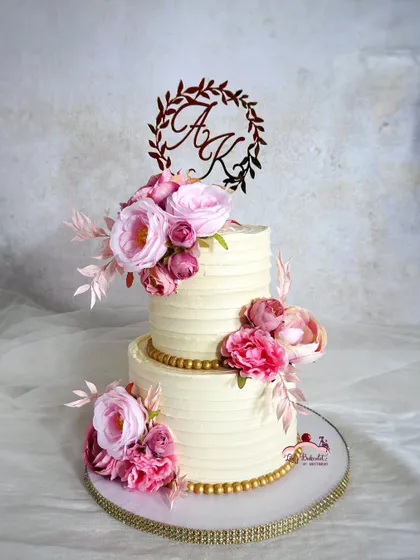 A floral beauty for an engagement celebration. This two-tier cake features textured buttercream and is adorned with beautiful pink flowers.