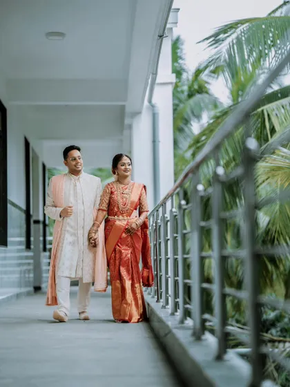 A beautiful shot of a couple walking hand-in-hand down an outdoor corridor, a classic post-wedding portrait.