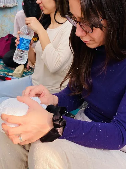 Concentration is key. A student works carefully on her puppet, with wood shavings all around. This is the real, messy, beautiful process of creating something by hand.