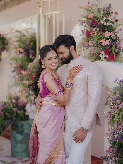 A classic engagement portrait against a stunning floral arch. The couple's embrace and the bride's beautiful Kanchipuram saree make for a timeless image.