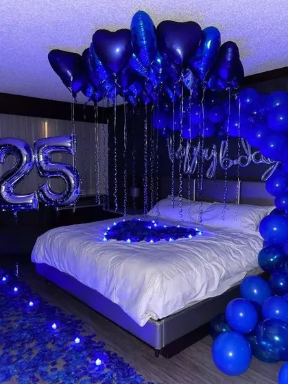 A striking 25th birthday theme using a bold royal blue. This setup includes a partial balloon arch, number foils, and blue LED lights on the floor, creating a cool and vibrant party space.