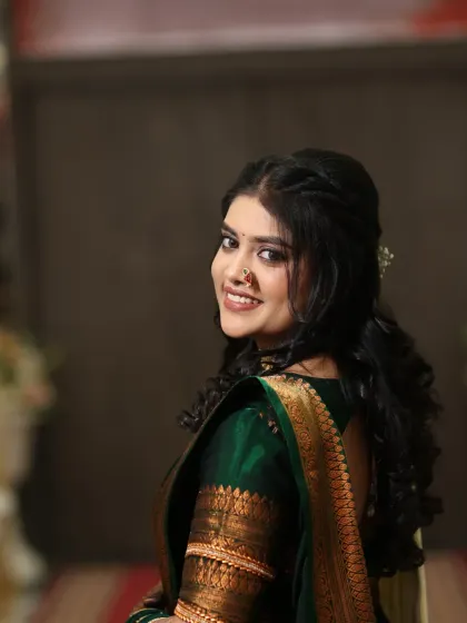 A lovely over-the-shoulder smile from the bride, showing off her soft curls and radiant makeup.