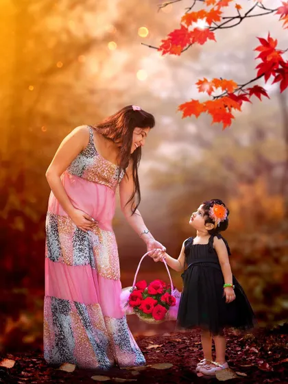 A pregnant mother and her young daughter hold hands in a beautiful, autumn-colored forest. This is a warm and loving portrait that celebrates the bond between them before the new baby arrives.