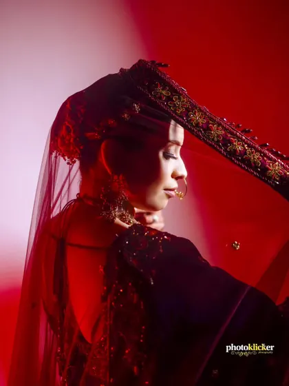 An artistic shot of the bride, with her veil creating a beautiful silhouette against a red-lit background.