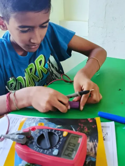 This student is carefully measuring the voltage of a lithium battery with a multimeter. We ensure every child understands the power source for their robots and circuits.