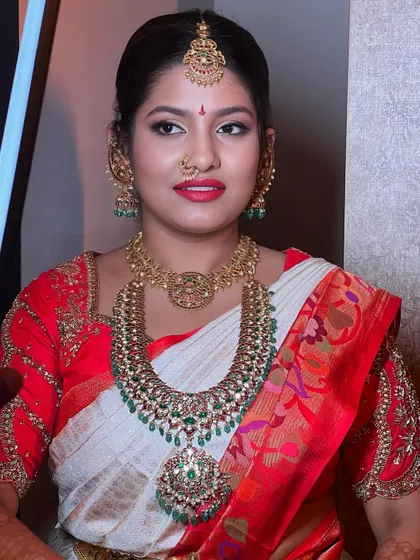 This bride's look is a perfect mix of traditional and modern. The makeup is glamorous with a pop of color on the lips, complementing her classic red and white saree.