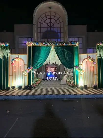 This elegant entrance structure combines rich emerald green drapes with white floral panels and a checkered floor. The design creates a sense of grandeur right at the entrance of the venue.