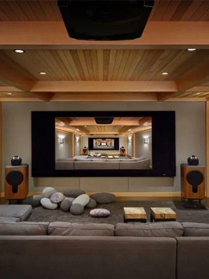 For a more relaxed and communal viewing experience, we design home theaters with large, comfortable sectional sofas. This setup, featuring a natural wood ceiling and professional-grade speakers, is perfect for family movie nights and casual entertainment.