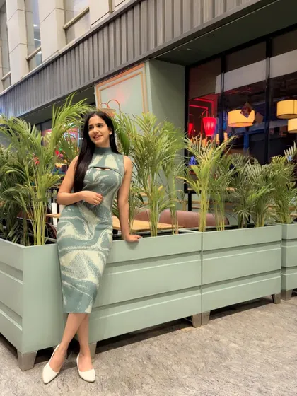 A relaxed and happy pose in the same dress, leaning against a planter. This shows a more casual and relatable side.