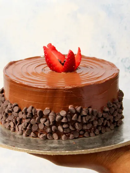 A hand holds up our signature plant-based chocolate chip cake. It’s a perfect example of our commitment to creating beautiful, healthy cakes for your celebrations.