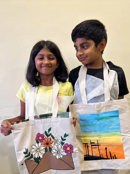 This brother and sister duo proudly display the tote bags they painted. It's a fun activity for siblings to do together, and they each get to show off their individual style.