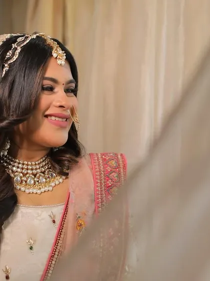 A lovely portrait of a bride in a soft pink and ivory lehenga, her makeup is dewy and fresh.