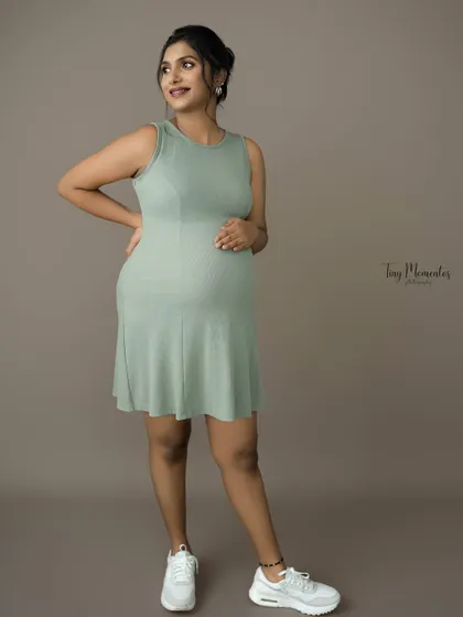 A modern and chic portrait in a casual ribbed dress. The simple styling and confident pose celebrate the beauty of pregnancy in an everyday, relatable way.