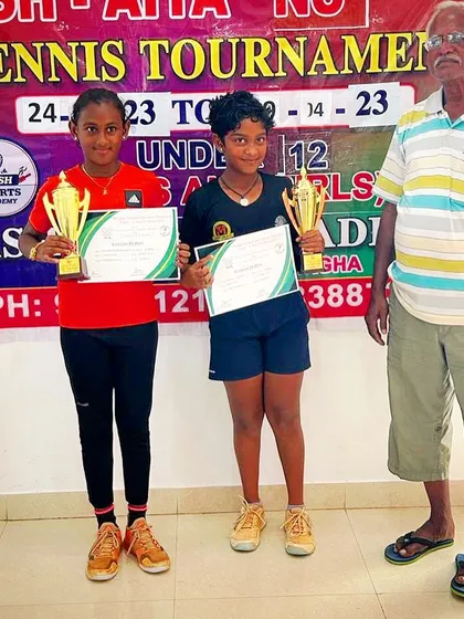 Eshita and her partner receiving their trophies from a tournament official at the AITA NS U-12 event.