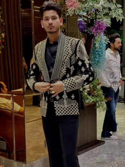 A client wearing a black tuxedo jacket with heavy gold and silver embroidery, perfect for a grand evening event.