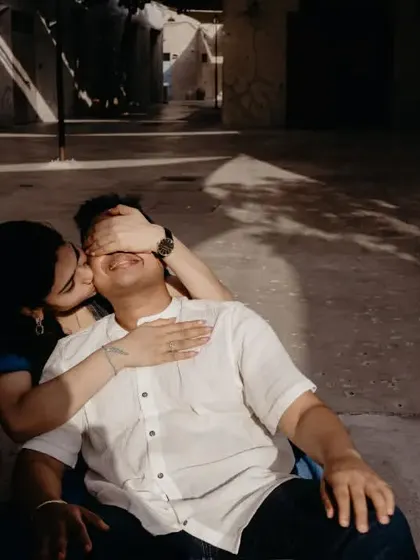 A sweet and playful moment where she covers his eyes and kisses his cheek. The beautiful shadow play in this Dubai alley adds an artistic and intimate touch.