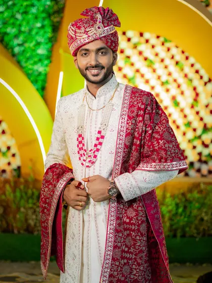 A handsome portrait of the groom, Deepak, in his ivory and red sherwani, ready for his grand wedding.