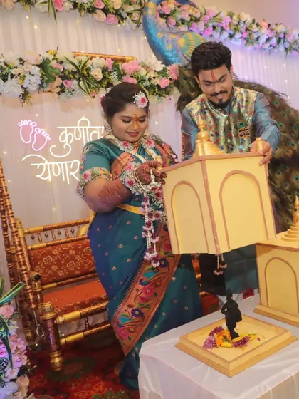 The couple revealing a baby boy figurine from the temple box during their peacock-themed Dohale Jevan ceremony.