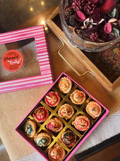 A top-down view of my assorted mini gujiyas, showcasing the different colorful designs. Each one is a little piece of art, packed neatly in a pink striped box, making it a delightful Holi gift.