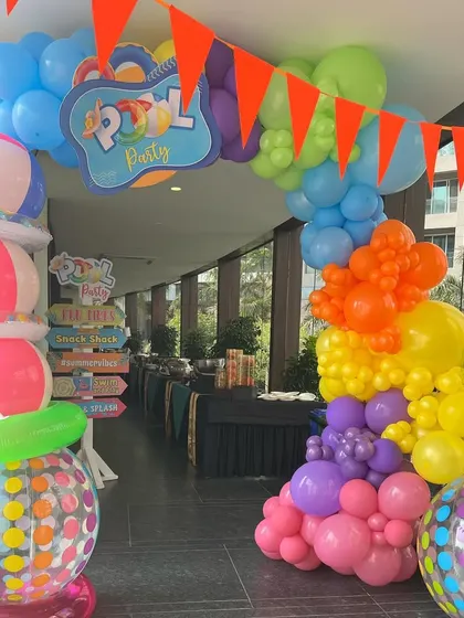 Another view of the lively pool party entrance, with a colorful balloon arch and stacked inflatable beach balls.