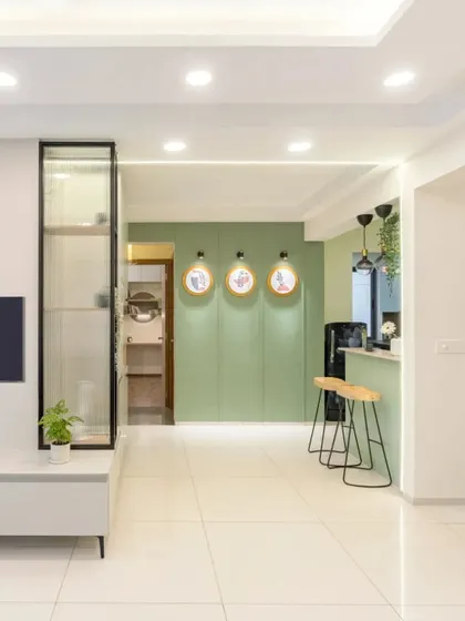 A modern living room with a sleek TV unit and a tall, fluted glass display cabinet. The subtle touch of sage green adds a sense of calm.